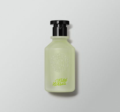 A perfume bottle with a green tint and a black cap, labeled 'Wild Horses' by the Rolling Stones
